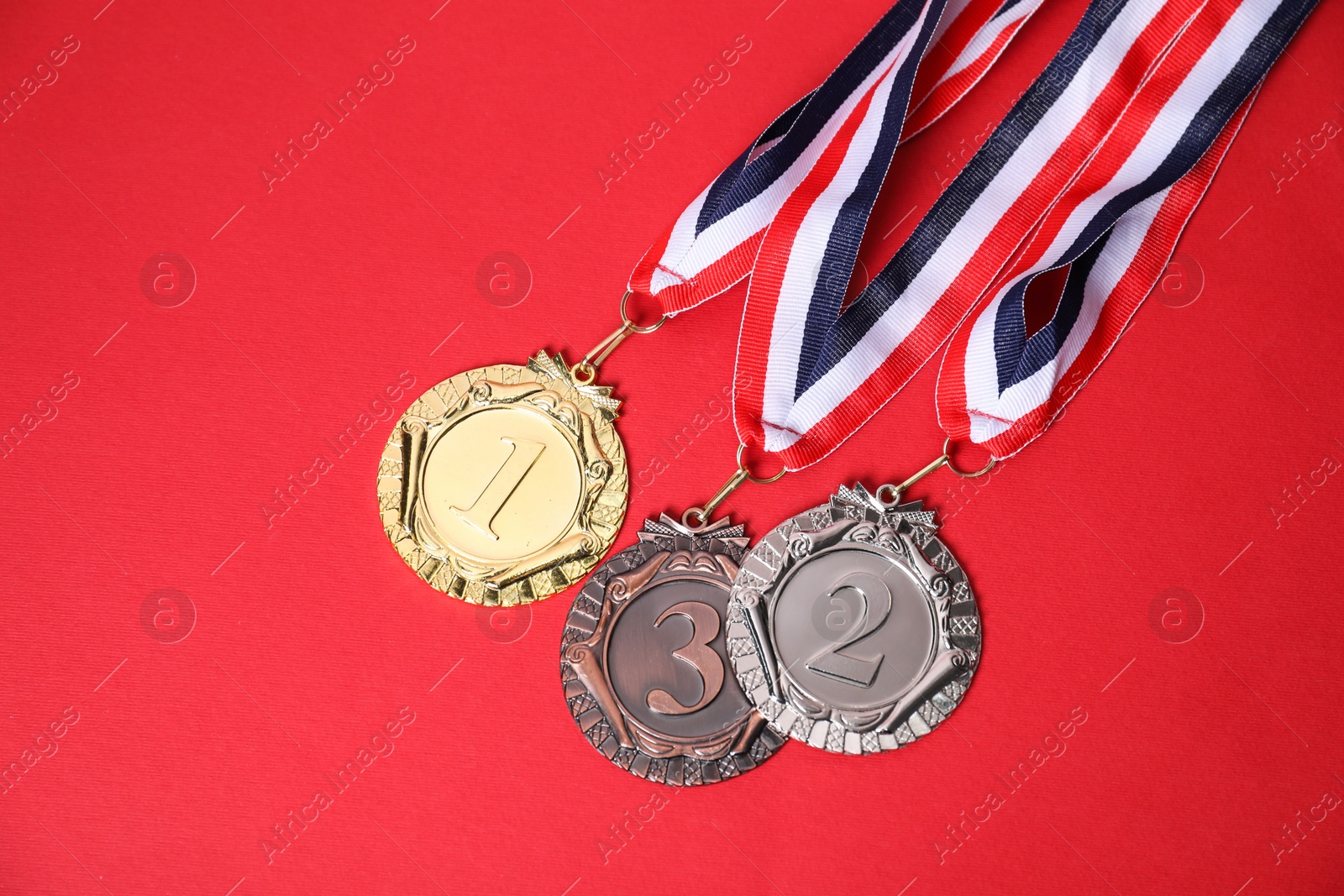 Photo of Golden, silver and bronze medals on red background, above view