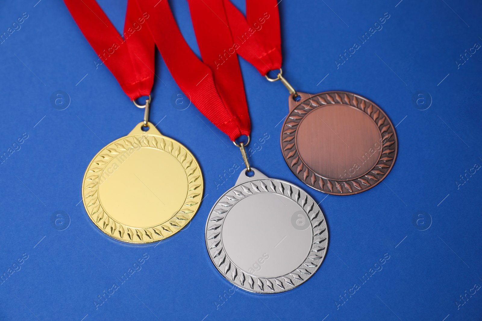 Photo of Golden, silver and bronze medals on blue background, closeup