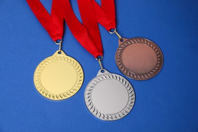 Photo of Golden, silver and bronze medals on blue background, closeup