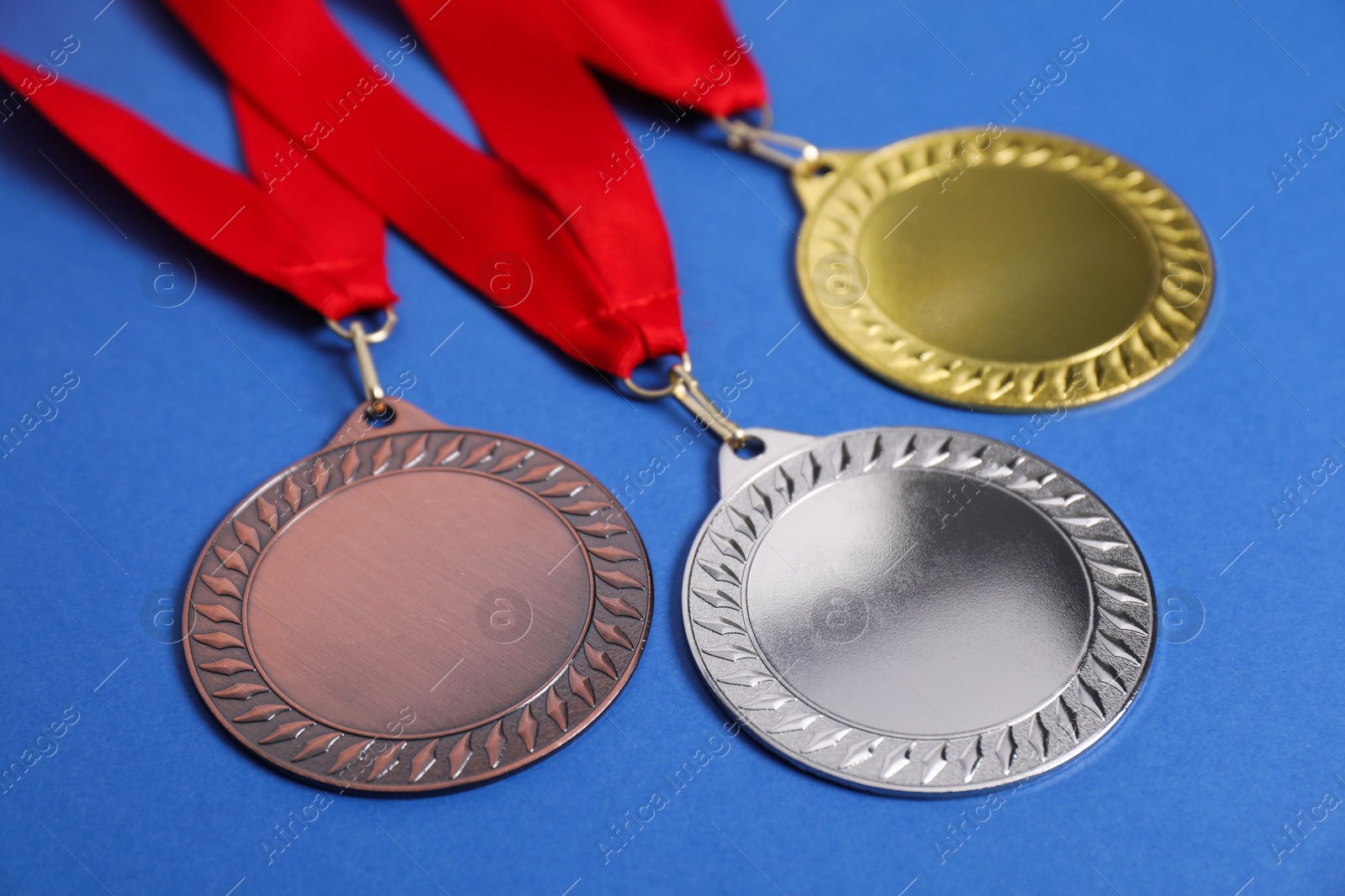 Photo of Golden, silver and bronze medals on blue background, closeup