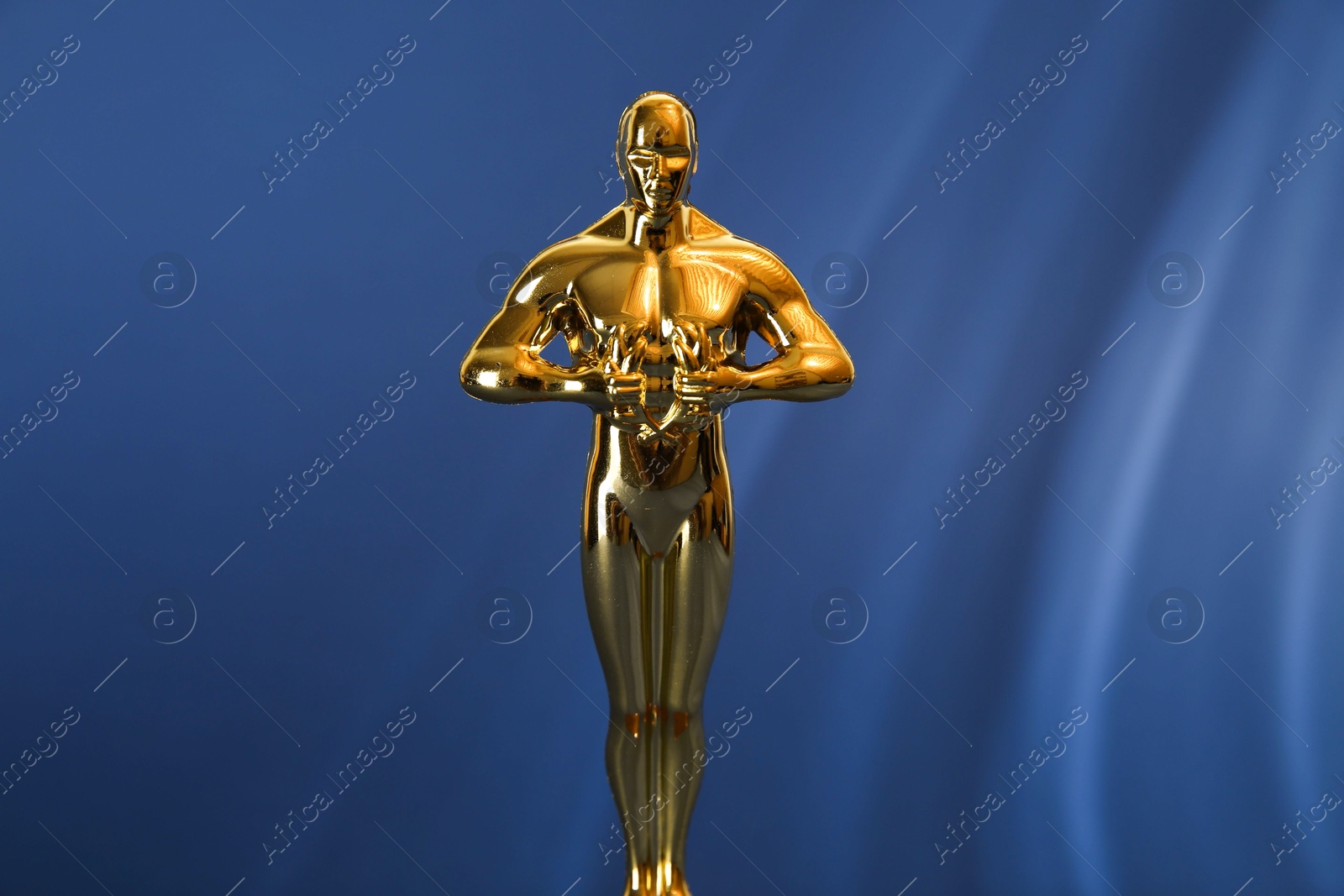 Photo of Golden trophy in shape of human figure on blue background