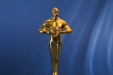 Photo of Golden trophy in shape of human figure on blue background