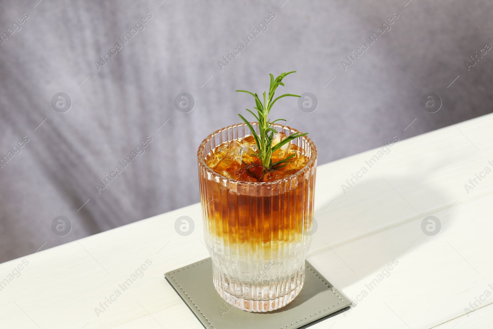 Photo of Refreshing espresso tonic drink with rosemary on white wooden table