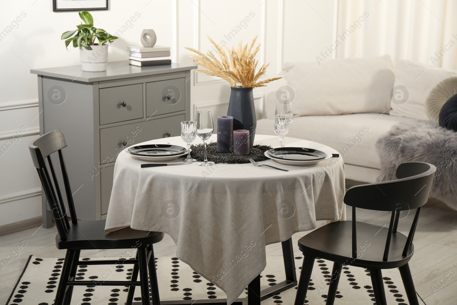 Photo of Stylish table setting with beautiful dishware and black chairs in dining room