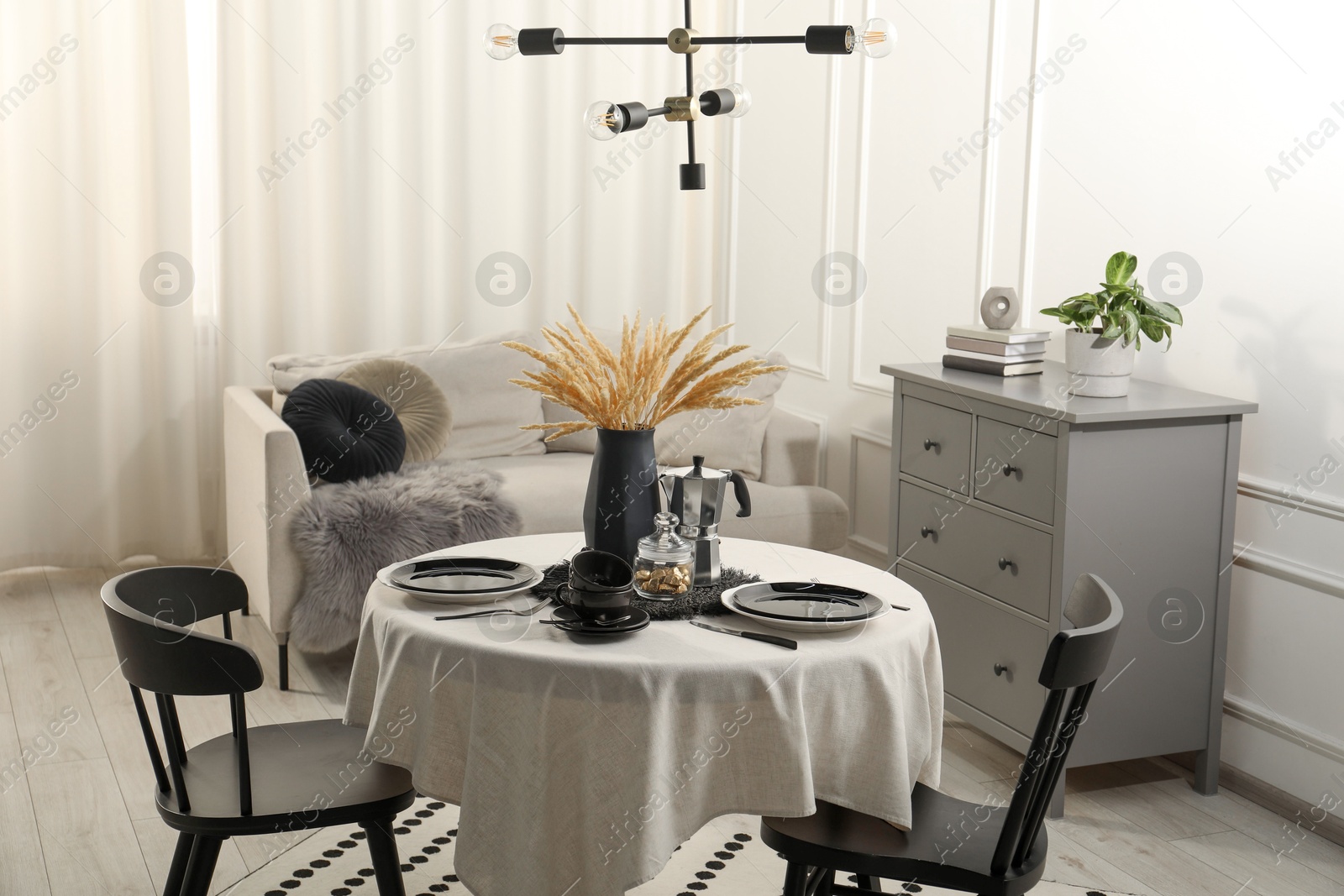 Photo of Stylish table setting with beautiful dishware and black chairs in dining room