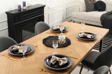 Photo of Stylish table setting with black dishware in dining room