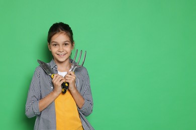 Photo of Girl with tools pretending to be gardener on green background, space for text. Dreaming of future profession