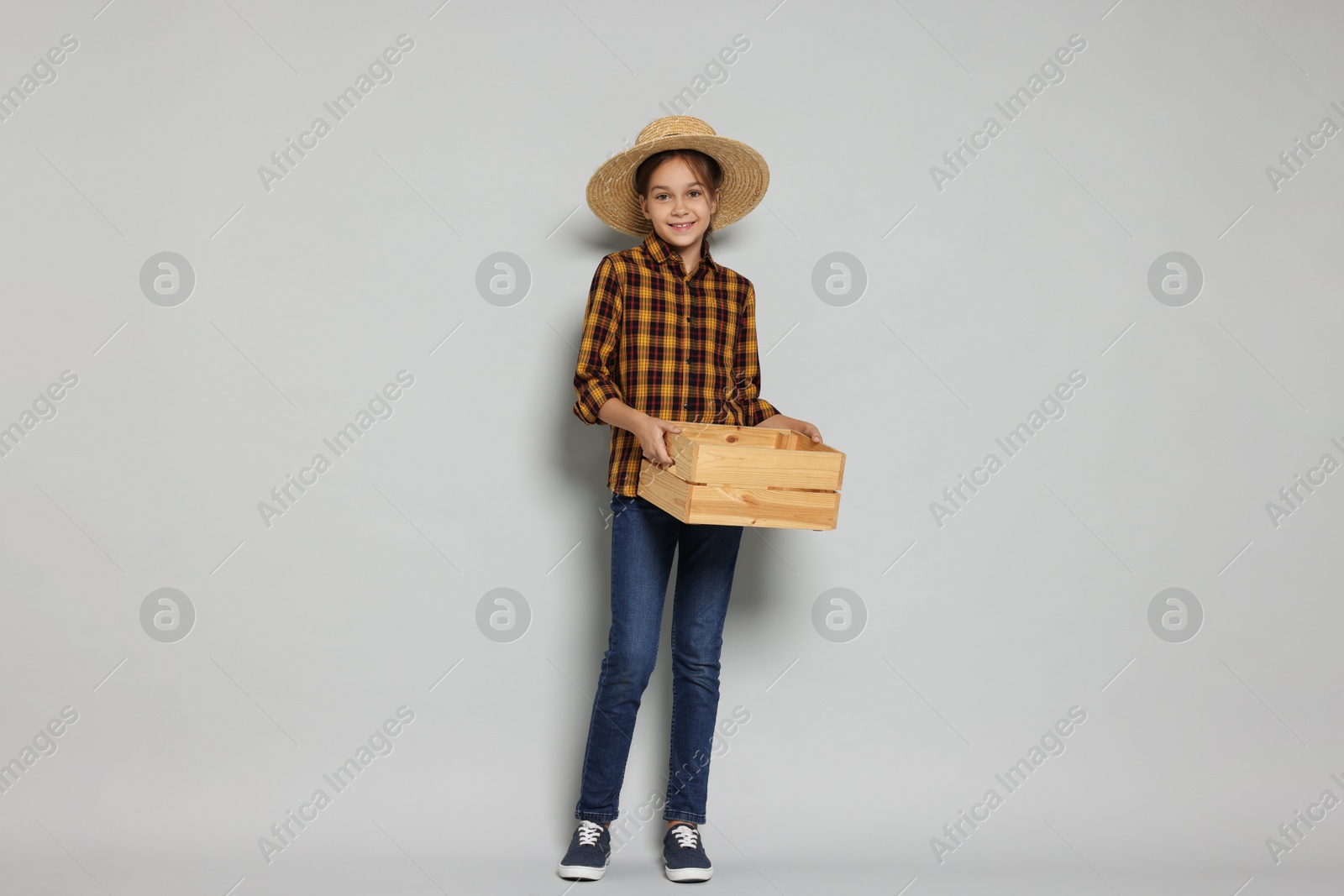 Photo of Girl with straw hat and wooden crate pretending to be farmer on light grey background. Dreaming of future profession