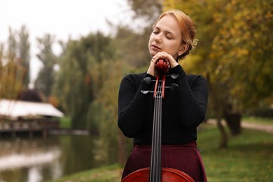 Photo of Beautiful young woman with cello in park