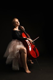 Photo of Beautiful young woman playing cello on black background