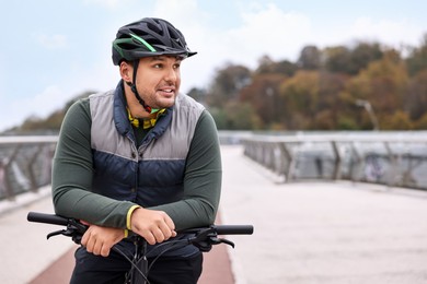 Photo of Man with helmet and bicycle outdoors, space for text