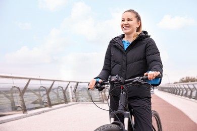 Photo of Woman with bicycle outdoors, space for text