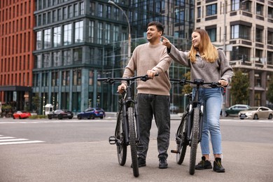 Photo of Beautiful happy couple with bicycles spending time together outdoors, space for text