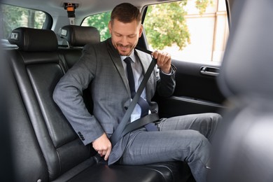 Photo of Man fastening seat belt in modern car