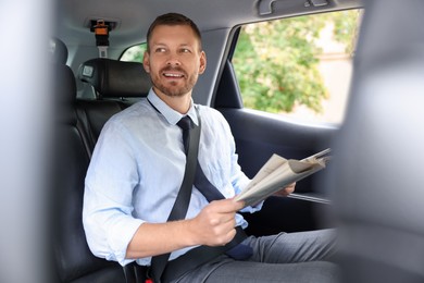 Photo of Handsome man with newspaper in modern car