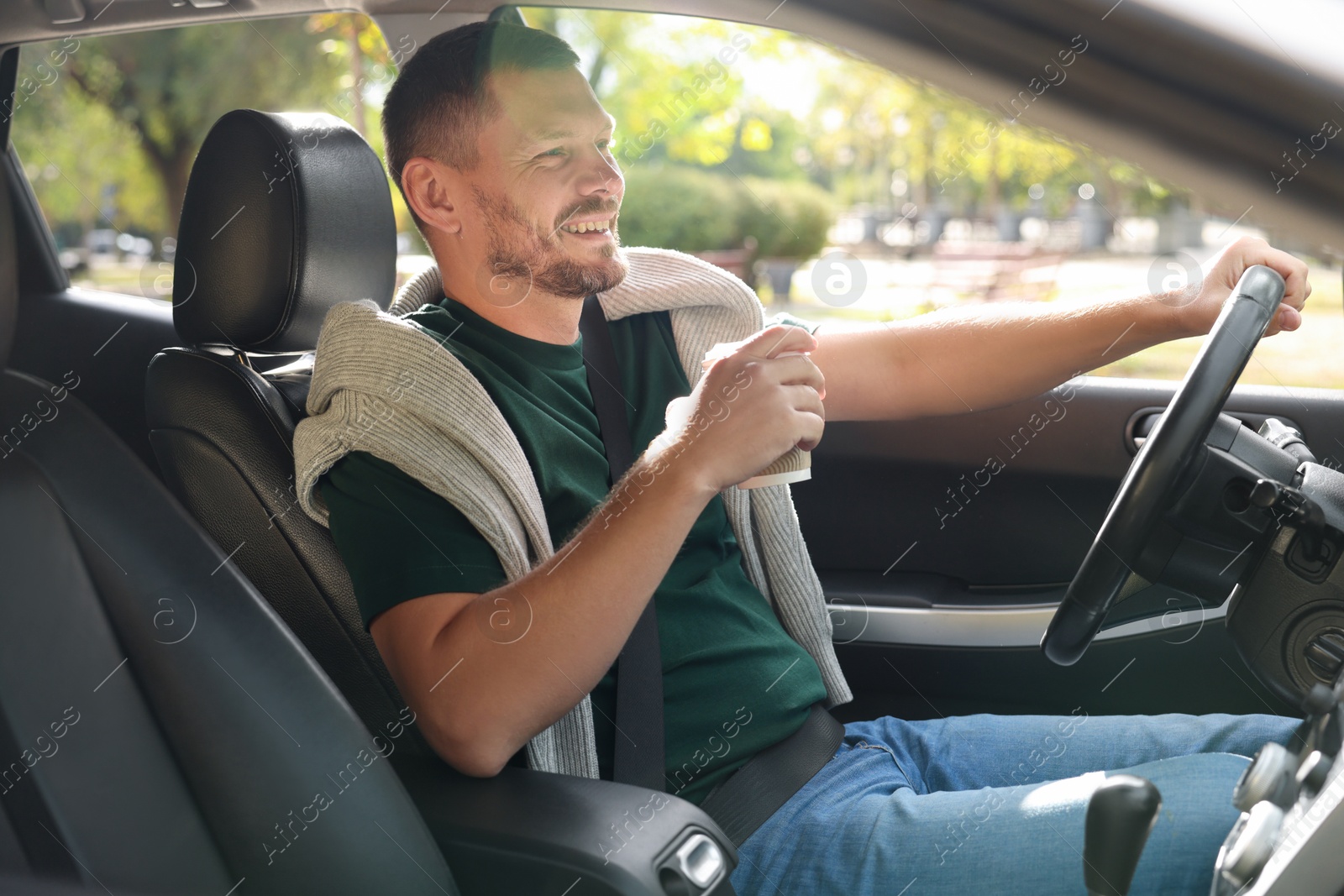 Photo of Man with cup of coffee driving modern car