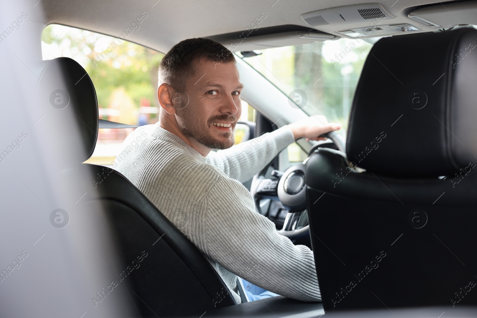 Photo of Happy man behind steering wheel of modern car