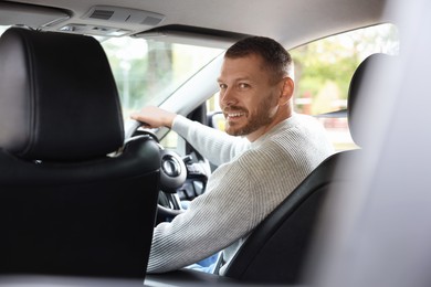 Photo of Happy man behind steering wheel of modern car