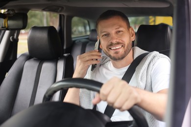 Photo of Man talking on phone while driving modern car, view through windshield