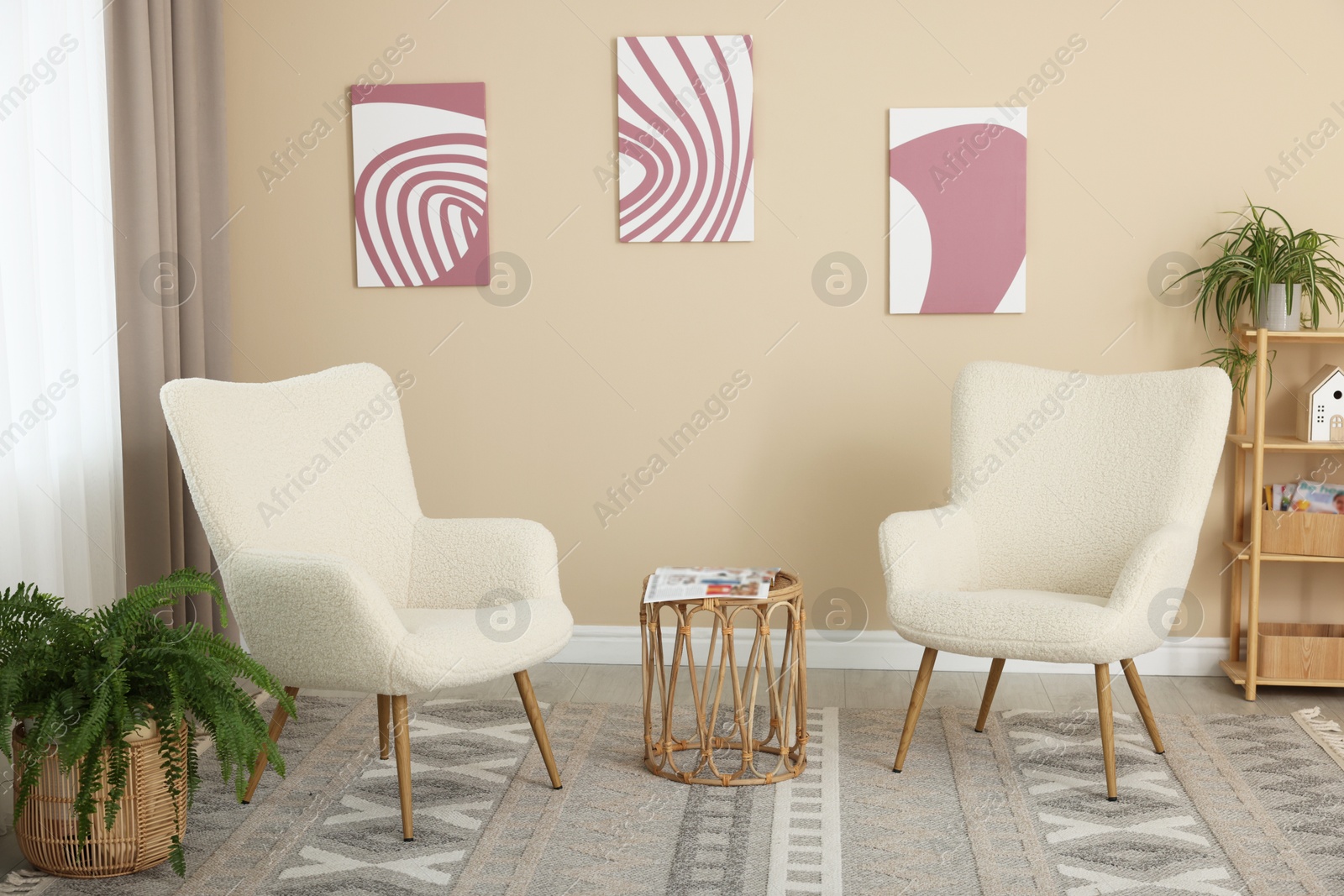 Photo of Soft armchairs and coffee table near beige wall indoors