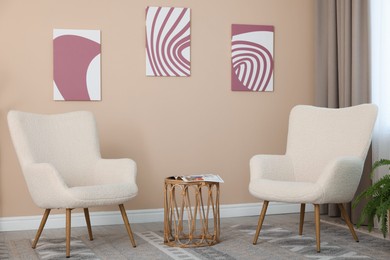 Photo of Soft armchairs and coffee table near beige wall indoors