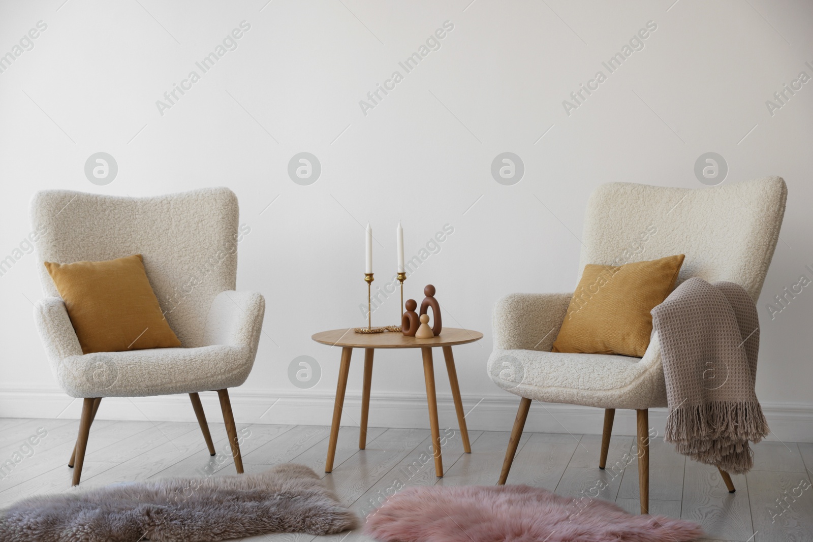 Photo of Soft armchairs and coffee table near white wall indoors