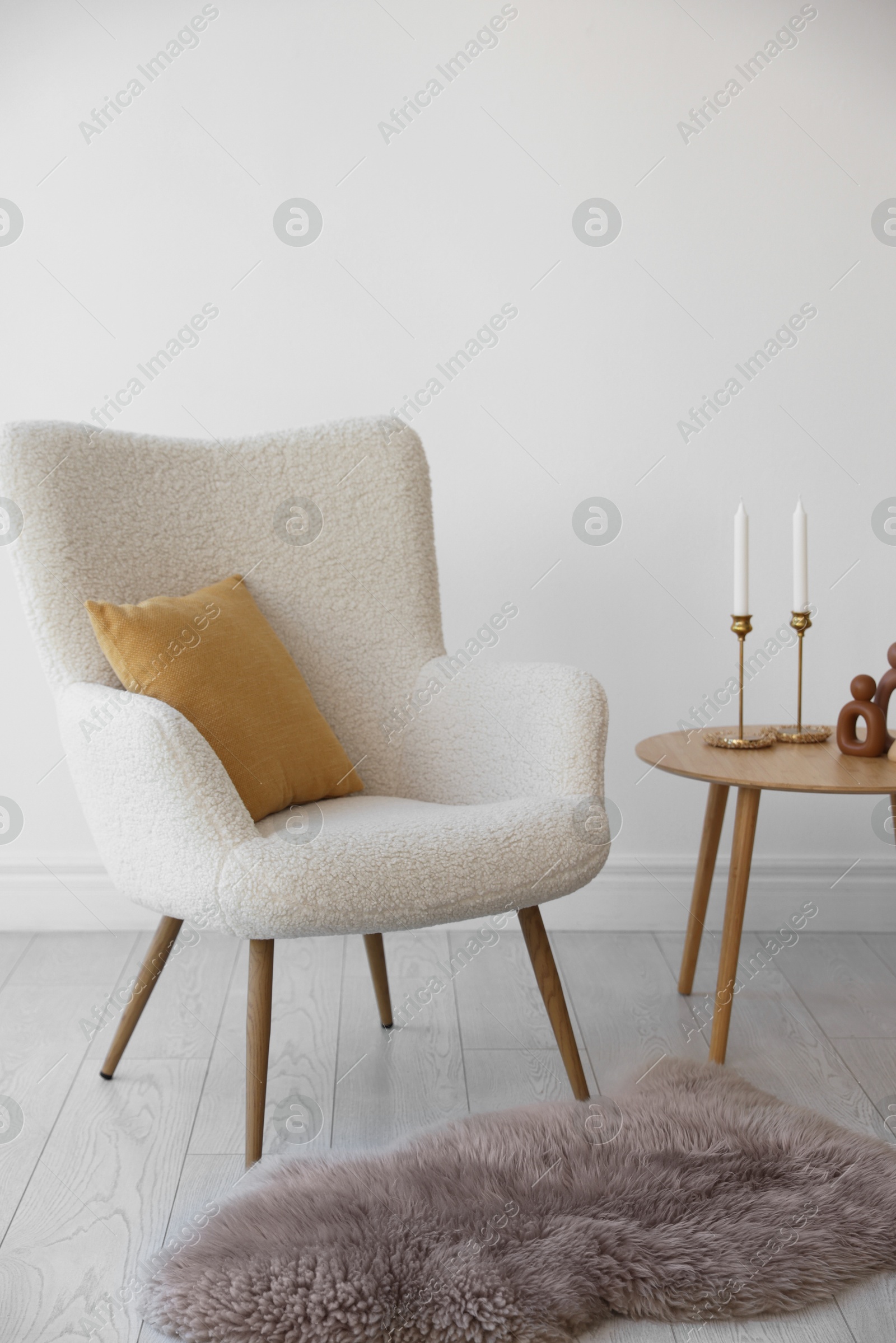 Photo of Soft armchair and coffee table near white wall indoors