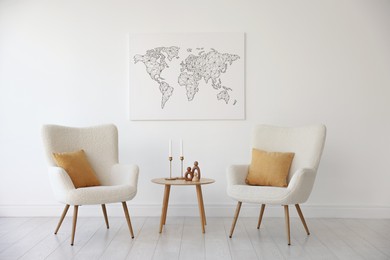 Soft armchairs and coffee table near white wall indoors