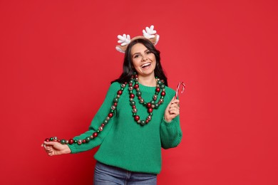 Photo of Beautiful woman with Christmas accessories and candy cane on red background