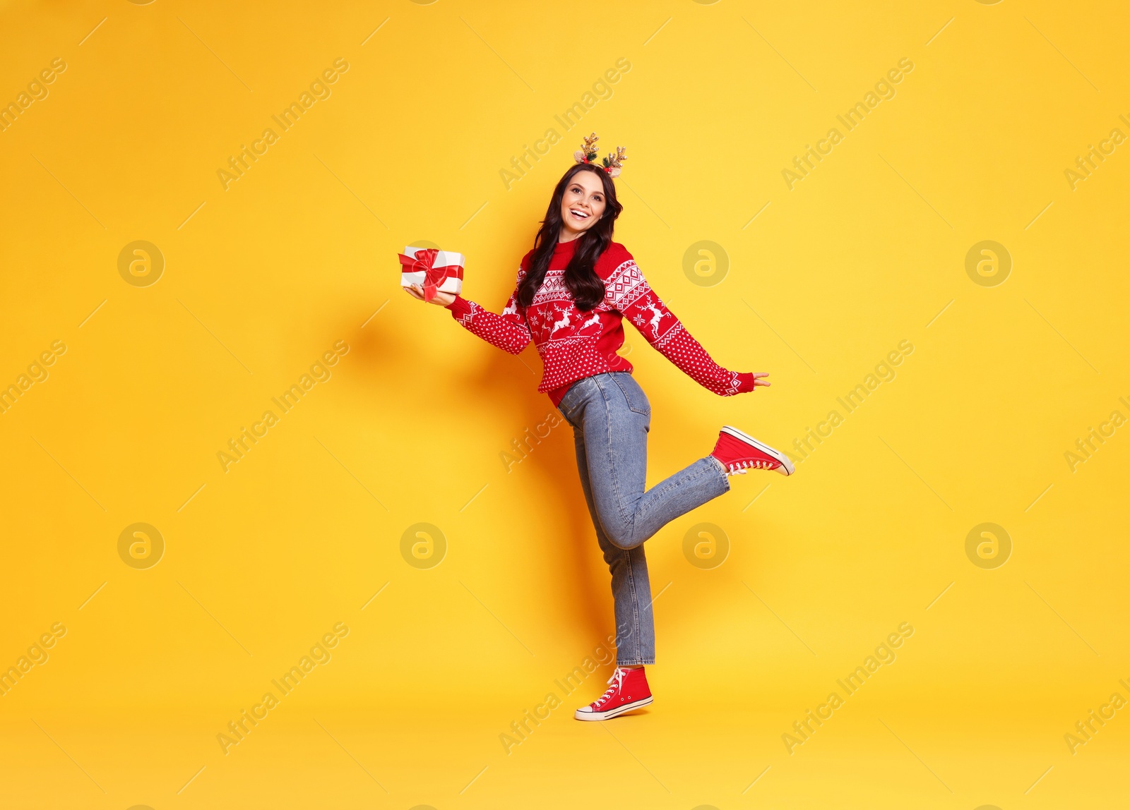 Photo of Happy woman with Christmas gift on yellow background