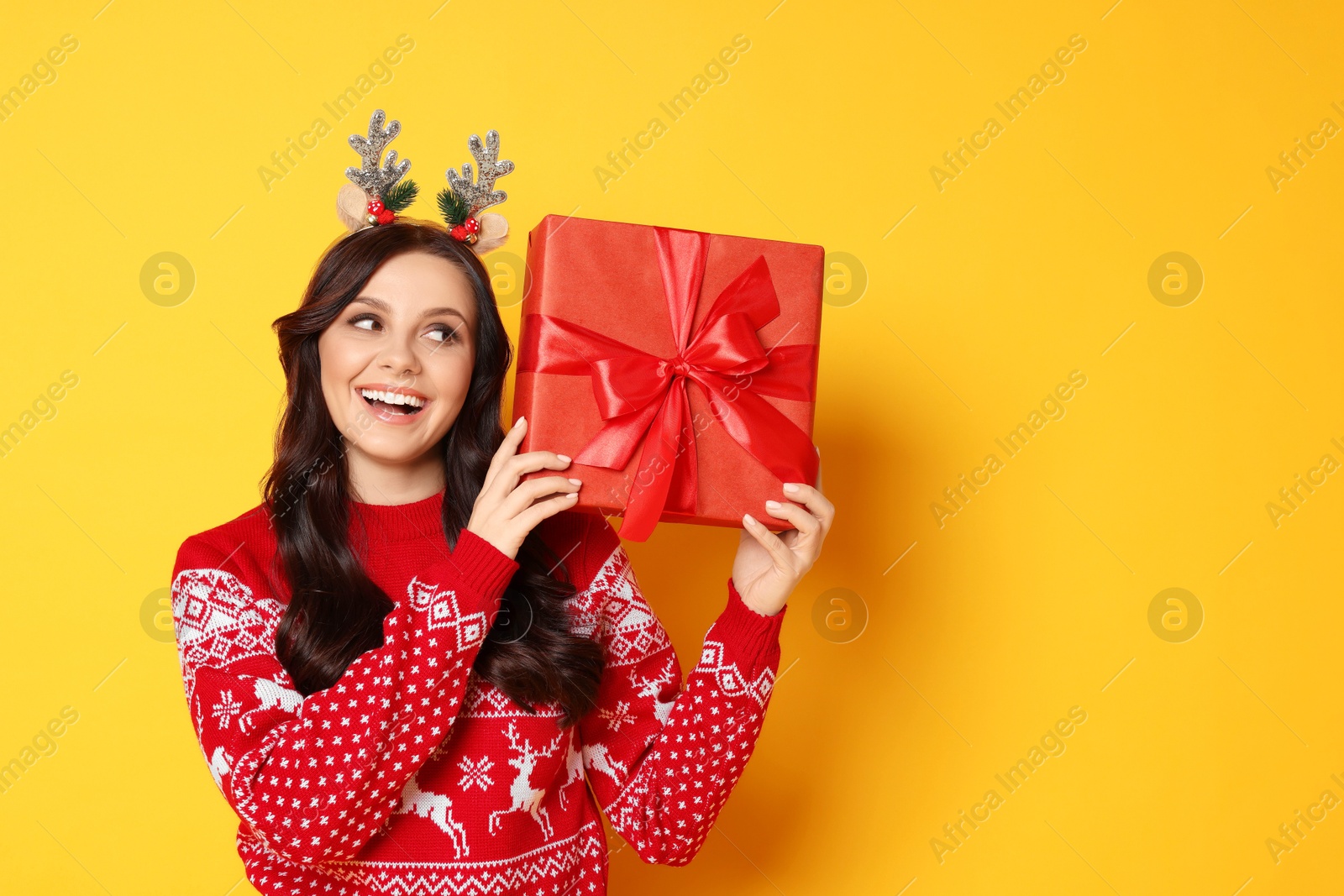 Photo of Happy woman with Christmas gift on yellow background