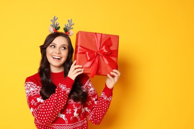 Photo of Happy woman with Christmas gift on yellow background