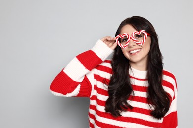 Photo of Happy woman with party glasses on light grey background, space for text. Christmas celebration