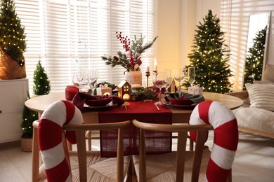 Photo of Christmas table setting with stylish dishware and festive decor indoors