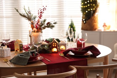 Photo of Christmas table setting with stylish dishware and festive decor indoors