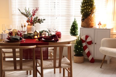 Photo of Christmas table setting with stylish dishware and festive decor indoors