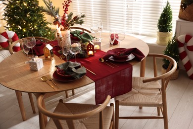 Photo of Christmas table setting with stylish dishware and festive decor indoors