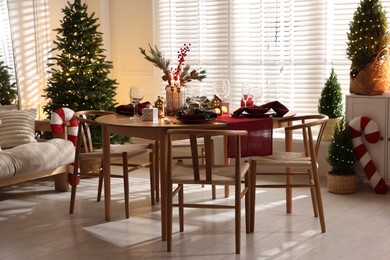 Photo of Christmas table setting with stylish dishware and festive decor indoors