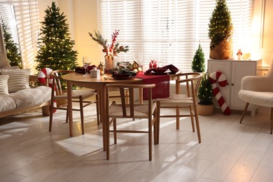 Photo of Christmas table setting with stylish dishware and festive decor indoors