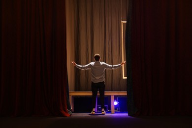 Photo of Professional actor rehearsing on stage in theatre, back view