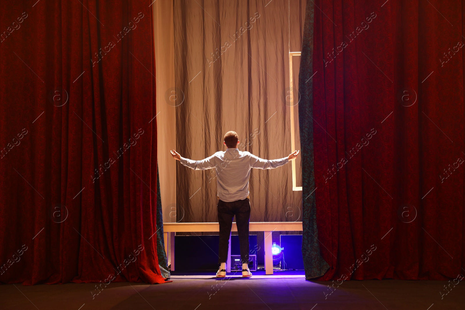 Photo of Professional actor rehearsing on stage in theatre, back view