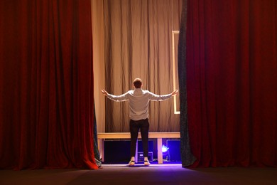 Professional actor rehearsing on stage in theatre, back view