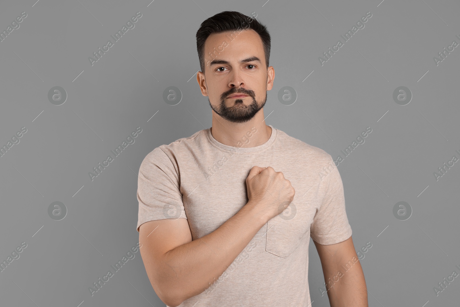 Photo of Man making promise on grey background. Oath gesture