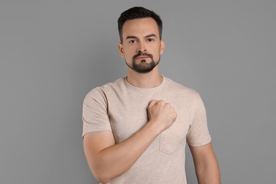 Photo of Man making promise on grey background. Oath gesture