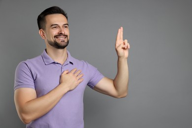 Photo of Man showing oath gesture on grey background, space for text. Making promise