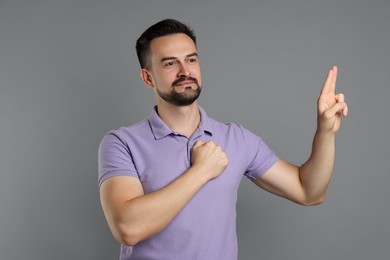 Photo of Man showing oath gesture on grey background. Making promise