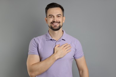 Photo of Man making promise on grey background. Oath gesture