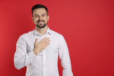 Photo of Man making promise on red background, space for text. Oath gesture