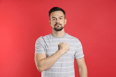 Photo of Man making promise on red background. Oath gesture