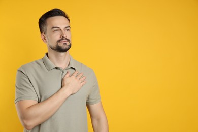 Photo of Man making promise on orange background, space for text. Oath gesture